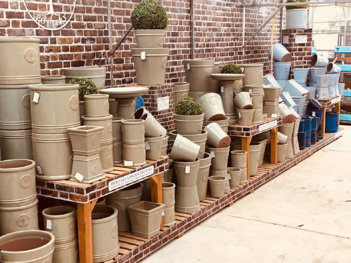 A range of Heritage Garden Pottery arranged on a stand with a printed brickwork facade.